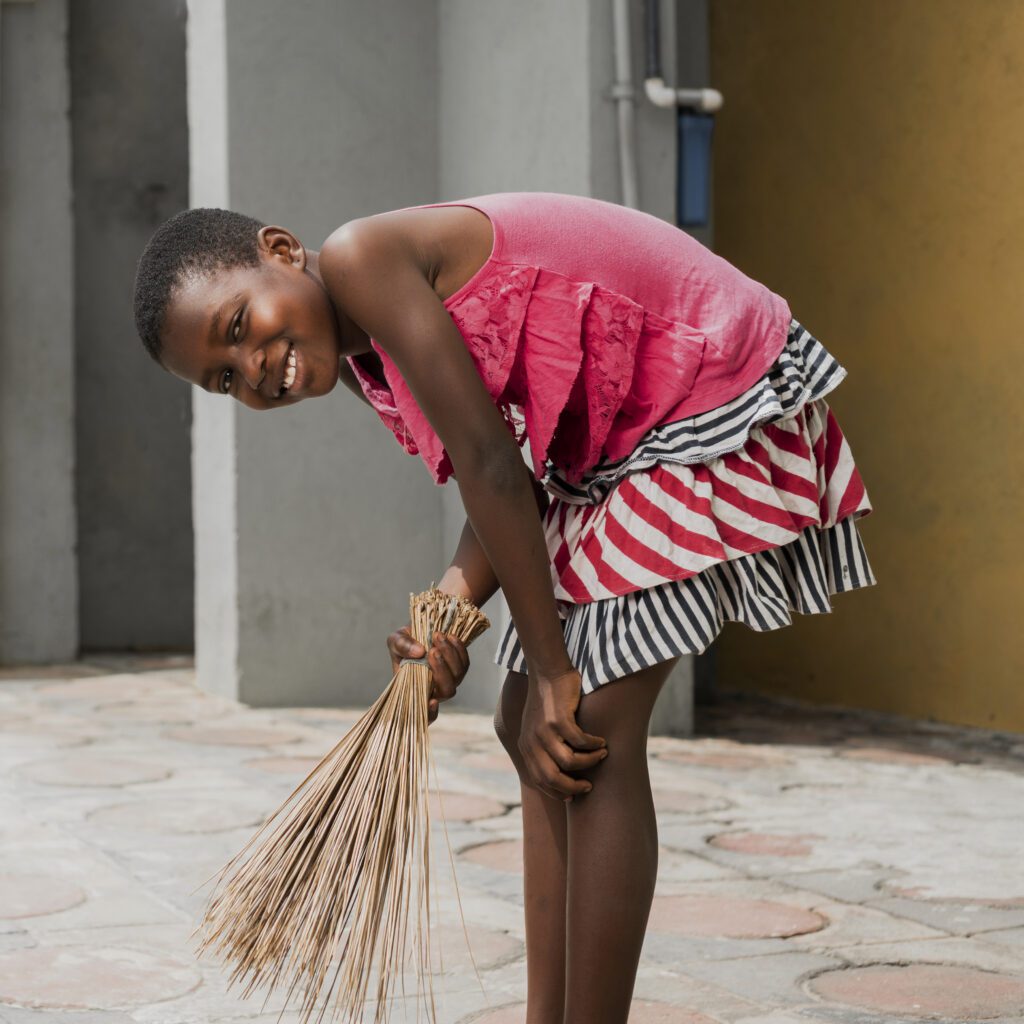 A Nigerian girl doing sweeping with a broom